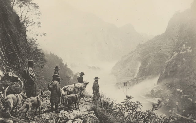 A vintage photograph of Matagi hunters with their Shikoku dogs in a mountainous setting